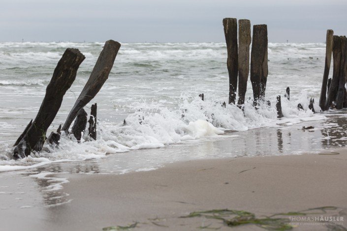 deutschland - Am Strand nach Dahme alte vereinzelte Holzbuhnen, durch die die Wellen brechen.