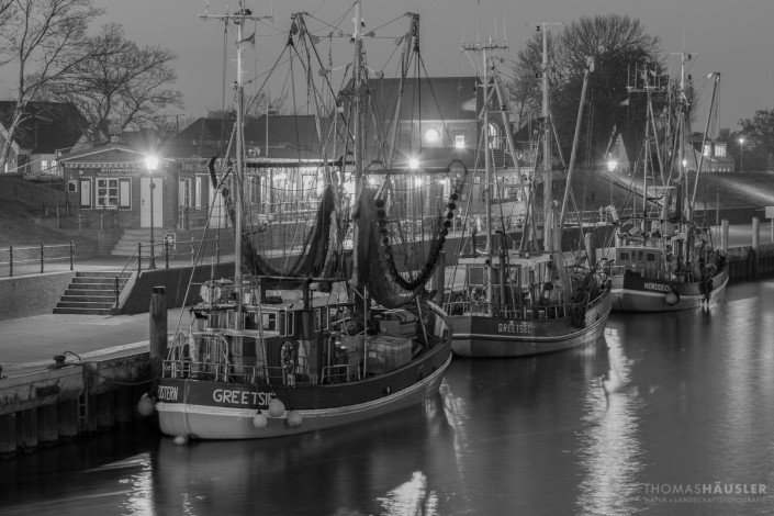 deutschland - Drei Krabbenfischerboote im Hafen von Greetsiel am Abend, eine Schwarz-weiß-Aufnahme