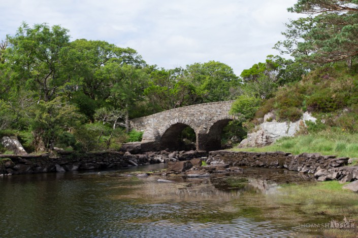 Irland - The bridge is situated at the spot known as the "Meeting of the Waters", where the three Killarney lakes meet. The waters from the Upper Lake flow into the Middle (or Muckross Lake) and Lough Leane.